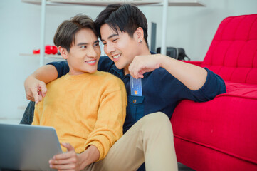 Asian homosexual couple in pajamas shopping online with computer notebook in the bed.Concept LGBT gay.