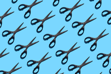 Open and closed black stationery scissors on a blue background. Pattern with stationery scissors. The concept of office supplies, school, student body, needlework.