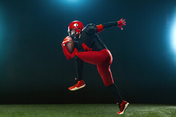 American football player, athlete sportsman in red helmet on dark background with smoke. Sport and motivation wallpaper. © Mike Orlov