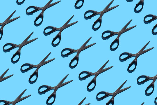 Open and closed black stationery scissors on a blue background. Pattern with stationery scissors. The concept of office supplies, school, student body, needlework.