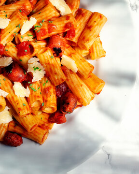 Plate of rigatone pasta with chorizo ​​and cheese on white plate. Overhead shot detail