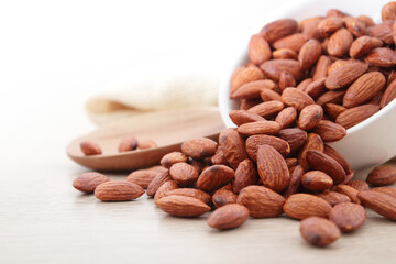 Almonds are in a white cup. Placed on a wooden floor. Food photography concept. Copy space