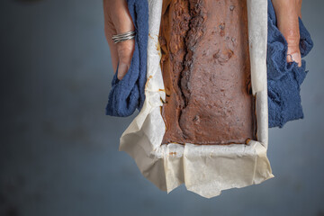 Several tomatoes on a table next to a basket and a blue cloth. Overhead view