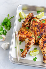 Thai Barbecued Whole Chicken on a Baking Tray with Cilantro, Lemon and Lemongrass Top Down Vertical Photo