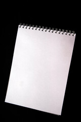 White notebook paper sheet isolated on black background. Top view