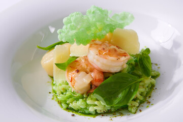 Delicious risotto with spinach, greens and prawns. Served in a modern dishware. Shallow dof