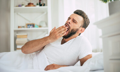 Close up photo of handsome young bearded man lying in bed and relaxing on the morning