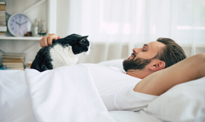 Close up photo of handsome young bearded man lying in bed and relaxing on the morning