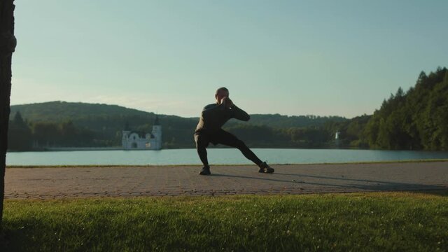 Close up man doing exercise jum near lake at outdoor workout at sunlight sportswear active sport runner fitness healthy jog outside running morning summer slow motion