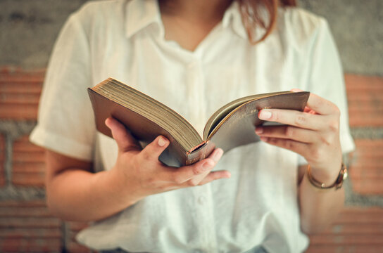 A young Christian woman closes her scriptures reading and studying in her room on Sunday.