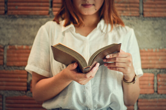 A young Christian woman closes her scriptures reading and studying in her room on Sunday.