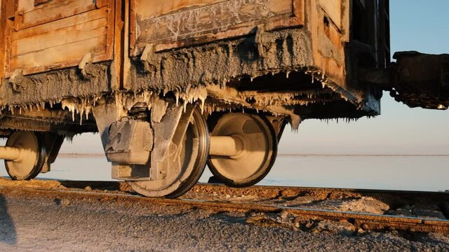 An old train travels by rail across a salt lake close-up. Extraction of salt in Lake Bursol. Russia. September 2020
