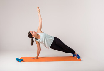 a woman makes a side plank and looks up on a white background with a space for text