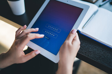 Crop female browsing tablet at workspase