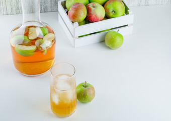 Apples in a wooden box with drink high angle view on white and grungy background