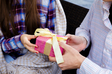 Obraz na płótnie Canvas Male and female hands holding a pink gift box.