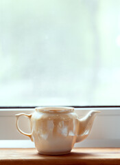 cup of tea on the table.  teapot by the window
