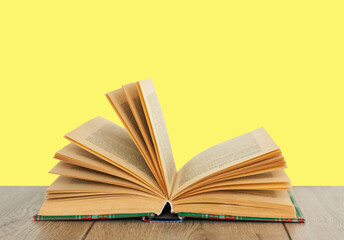 Open book textbook in colorful cover on a yellow background. Back to school distance home education.Quarantine concept of stay home.