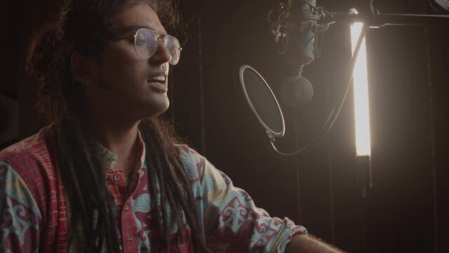 Music production studio. Inspirational men. Indian man recording the podcast. An intelligent brunette male person records voice over.