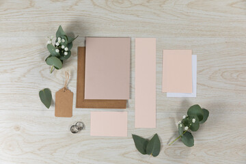 Notebook and pink sheet of papers surrounded by flowers on wood table