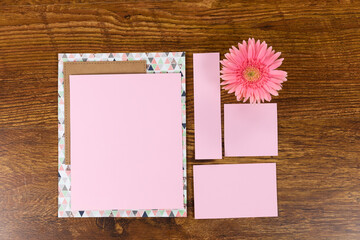 Pink sheet of papers surrounded by a flower on wood table