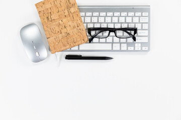 View of a keyword with glasses and a notebook with a pen in a white background