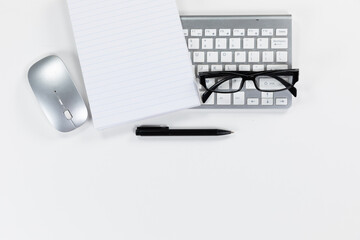 View of a keyword with a notebook, a pen and glasses on white background
