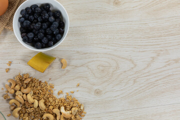 View of a variety of nuts and muesli, bowls of dried and fruits and eggs on wooden surface