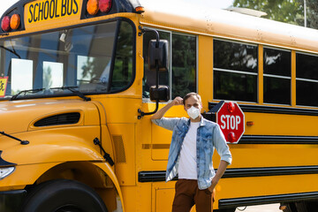masked bus driver looking at camera outside the elementary school