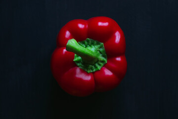  one red bell pepper on a black background top view