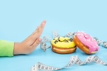 Diet or good health concept. hand rejecting unhealthy food like donuts or dessert isolated on blue...