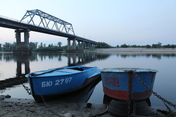 evening urban rural landscape two boats by the river under the bridge on a cloudy day