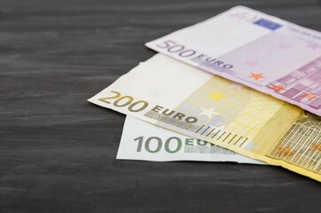 100, 200, 500 euro banknotes on a black wooden background.