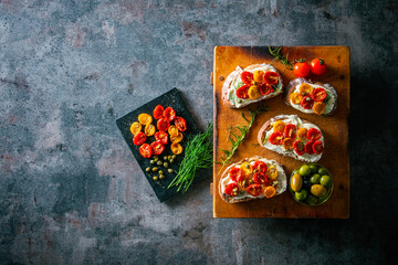 Sliced bread with cream cheese and homemade dried tomatoes on wooden board.Delicious snack.
