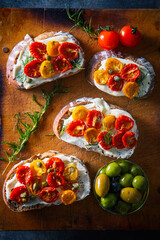 Sliced bread with cream cheese and homemade dried tomatoes on wooden board.Delicious snack.
