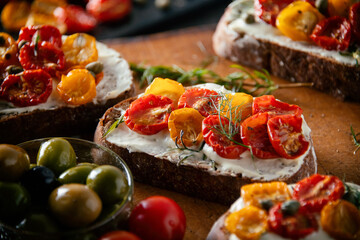 Sliced bread with cream cheese and homemade dried tomatoes on wooden board.Delicious snack.
