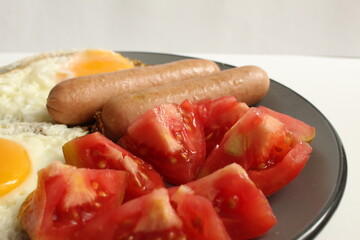 Breakfast eggs sausages salad vegetables red tomatoes on a gray plate on a white light background copy space