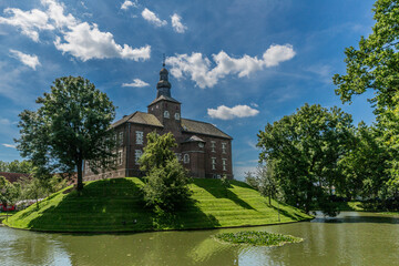 Fototapeta na wymiar Limbricht castle surrounded by water and green trees, wonderful sunny day with a blue sky and white clouds in south Limburg in the Netherlands Holland