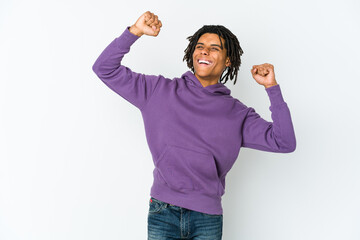 Young african american rasta man celebrating a special day, jumps and raise arms with energy.