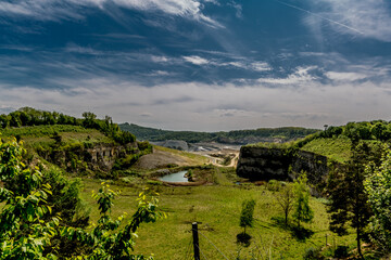 Scenic landscape view against the sky of Sint Pietersberg or Mount Saint Peter, Dutch canyon, green vegetation, the old marl quarry with cement factory in the background, Maastricht in the Netherlands