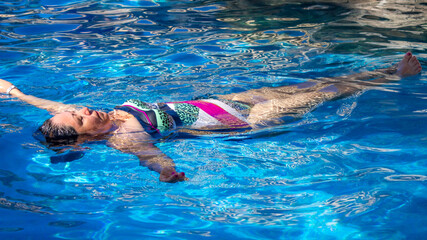 Woman floating relaxed in a swimming pool with crystal clear water, sunny day in Puerto Vallarta, Jalisco, Mexico