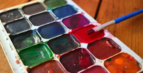 Multicolored palette of watercolor paints with brushes. Art, drawing.