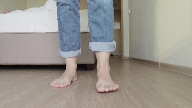 Woman taking off her clothe sin order to go to bed, bare feet close up, clothes falling down to the floor