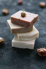 Homemade floral soap. Natural soap and rose flowers on dark background. Spa concept, body care products. Flat lay, top view