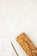 Fresh homemade pumpkin bread with pumpkin puree, cinnamon, nutmeg and seeds, placed on white background, photographed overhead, bread recipe. Copy space.