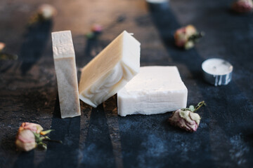 Homemade floral soap. Natural soap and rose flowers on dark background. Spa concept, body care products. Flat lay, top view