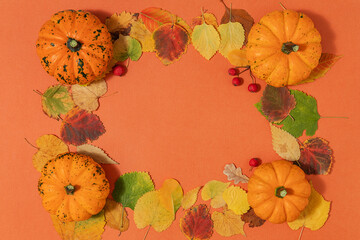 Creative autumn composition. colored pumpkins and bright leaves on an orange paper background with...