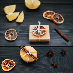 Natural handmade soap with dried slices of oranges and cinnamon on a dark background. Concept of Spa, body and skin care.  