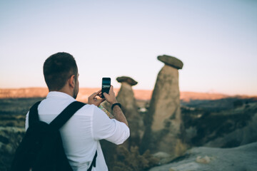 Fototapeta premium Faceless man with backpack taking photo of nature