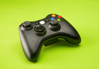 Video game control supported on a green background surface, selective focus.